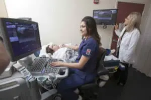 diagnostic medical sonographer salary: technician doing sonogram on patient with doctor watching